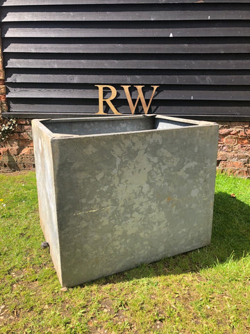 Gray rectangular galvanised metal trough planter with weathered rustic finish and chipped paint for herb garden