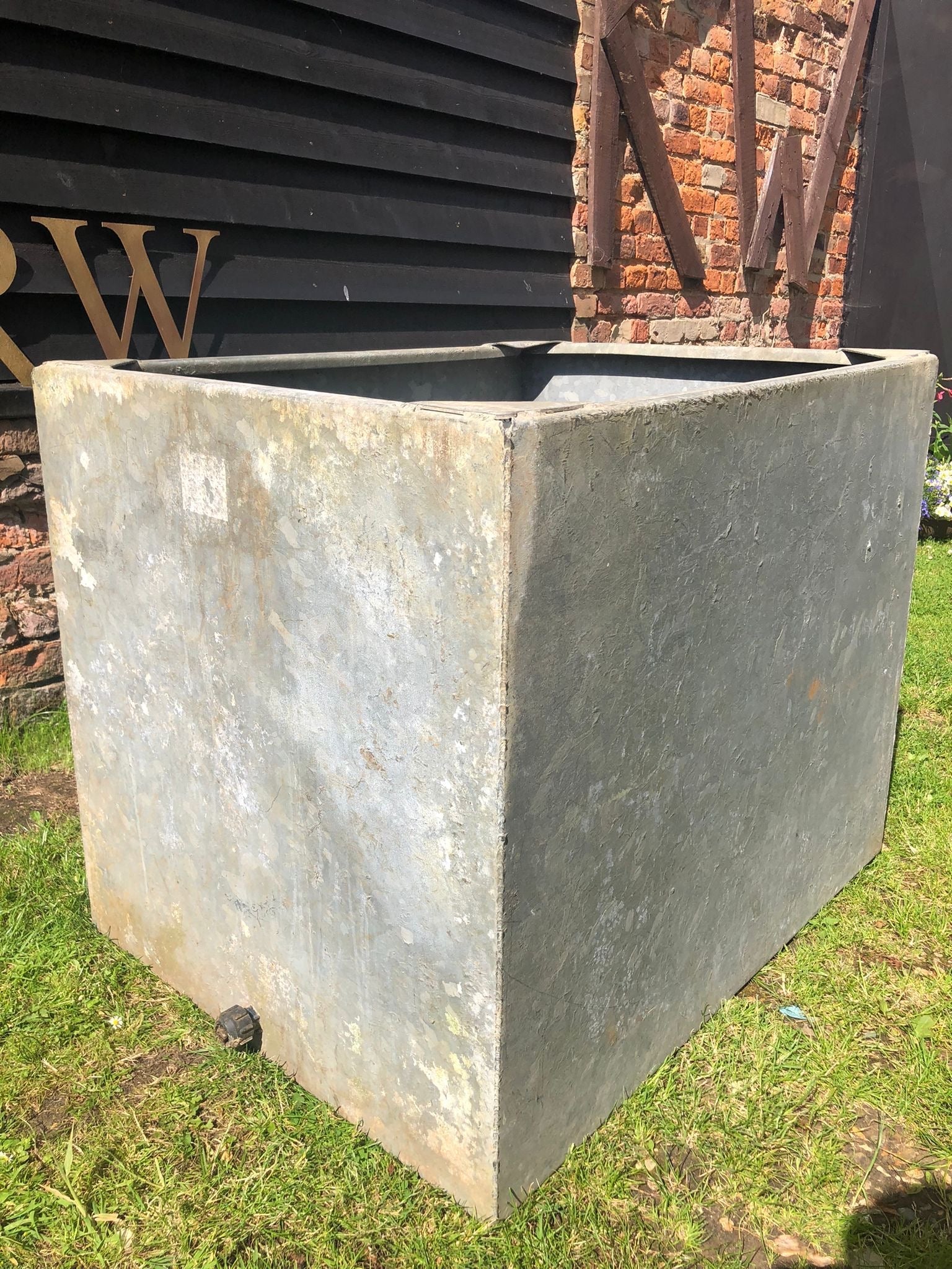 A weathered matte gray vintage galvanised metal trough planter perfect for herb garden or raised bed use