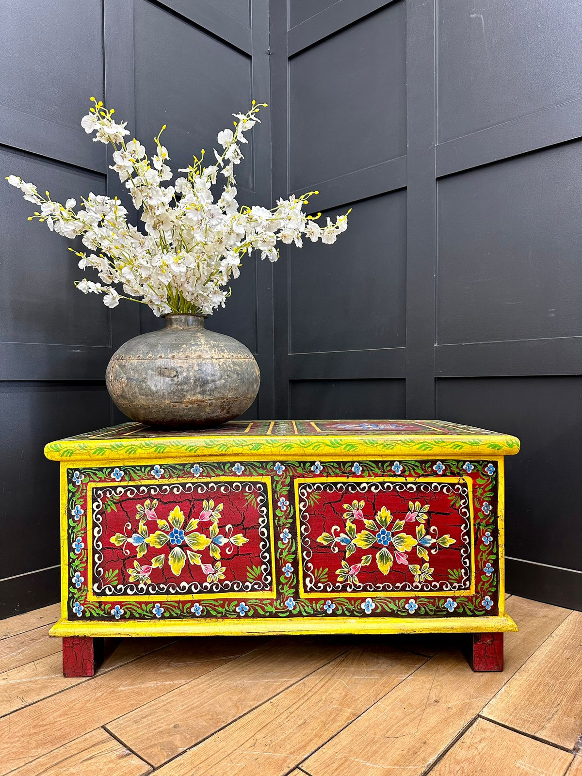 Vintage indian hand painted wooden chest in vibrant yellow and red with floral designs used as coffee table