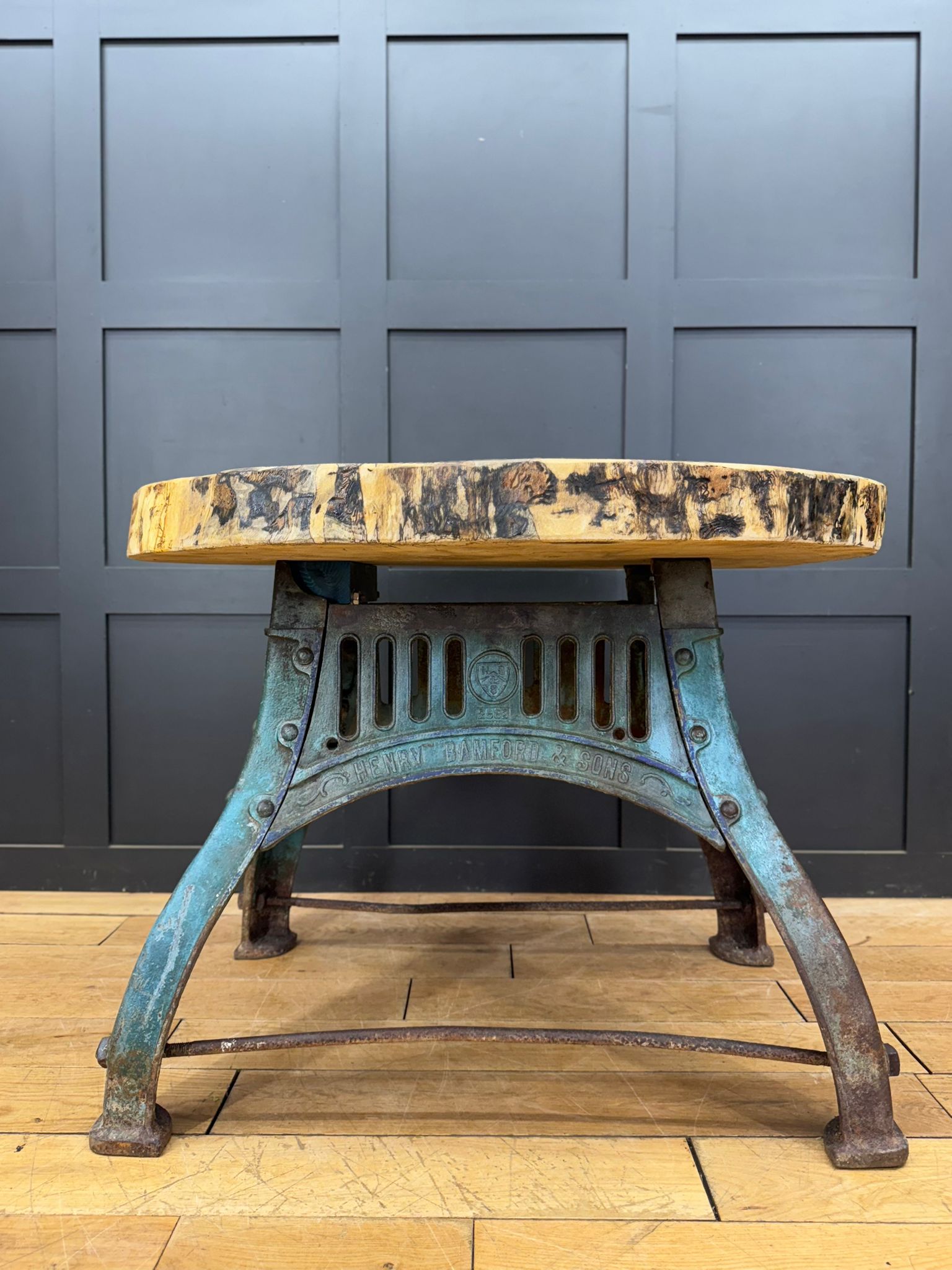 Industrial-style stool with rustic live-edge wooden top and weathered turquoise metal legs on cast iron base