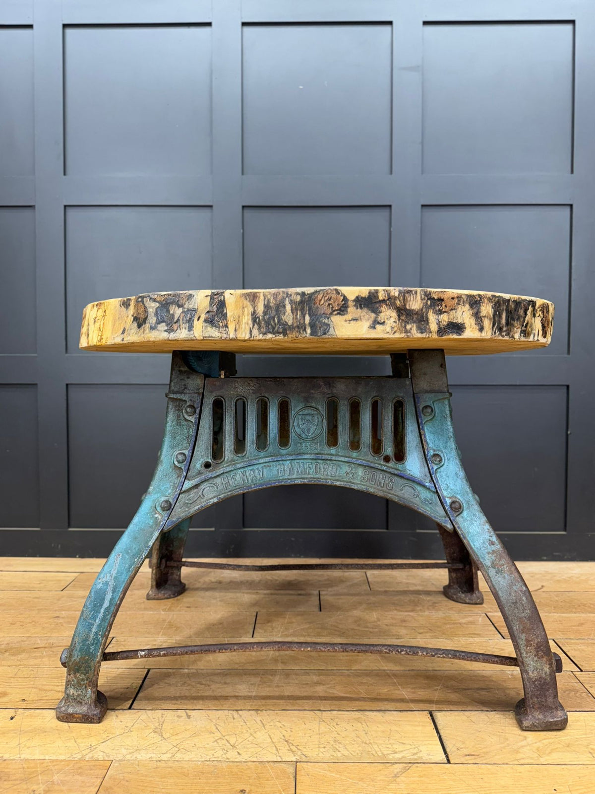 Industrial-style stool with rustic live-edge wooden top and weathered turquoise metal legs on cast iron base