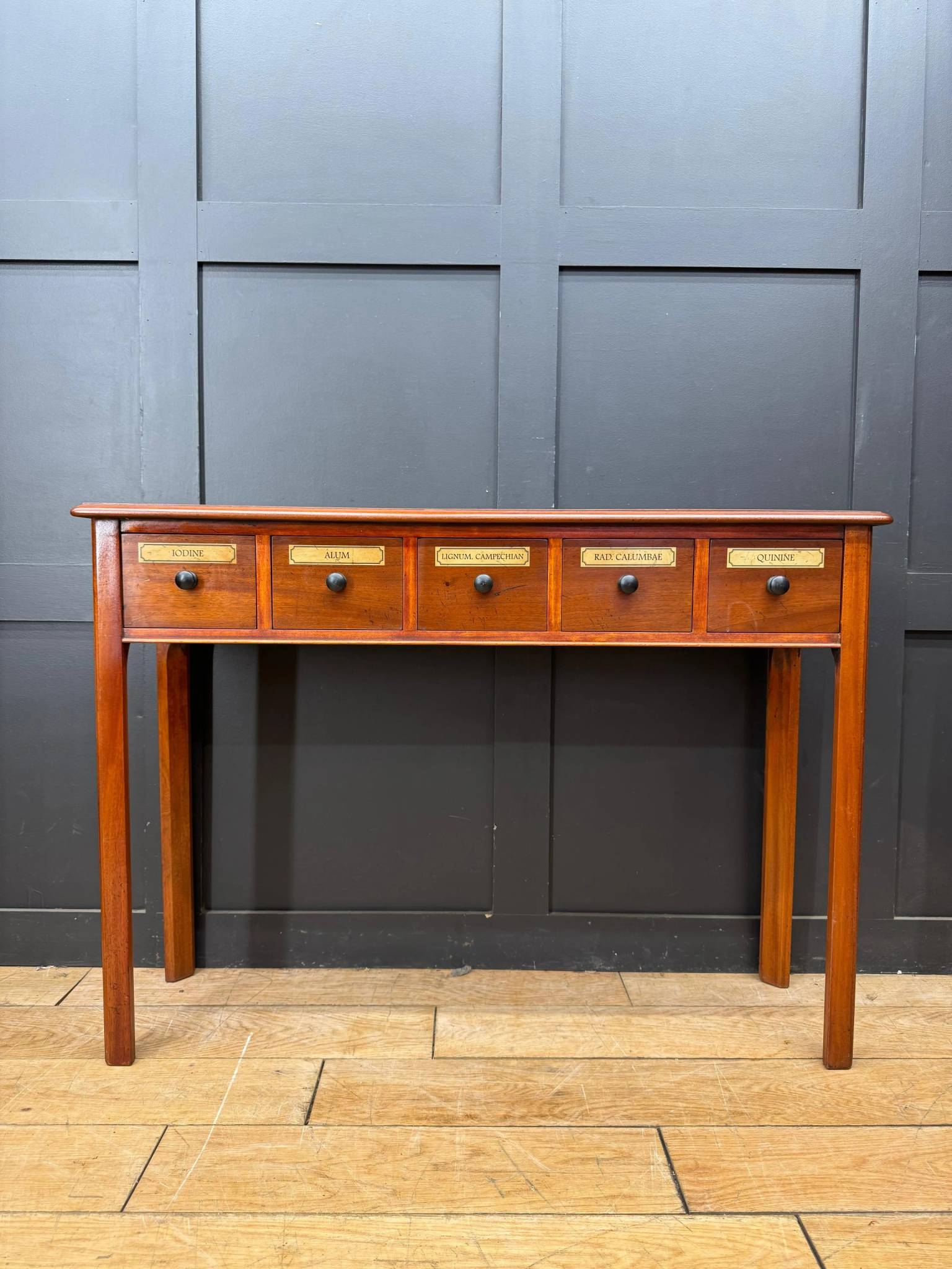 Vintage mahogany apothecary style console table with five labeled drawers and black round knobs perfect as a sideboard