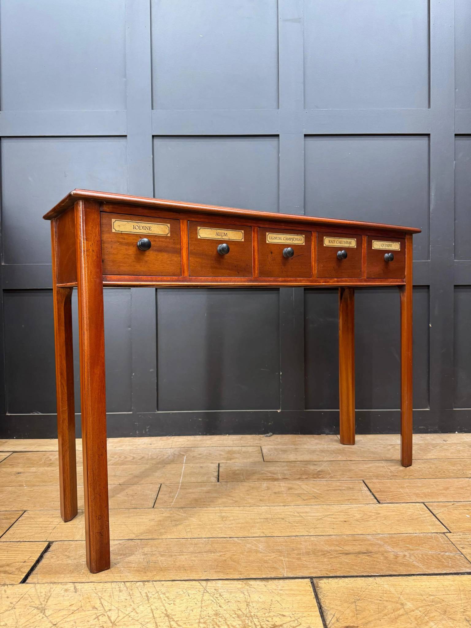 Vintage mahogany apothecary style console table with five drawers featuring brass labels and black round knobs