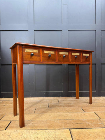 Vintage mahogany apothecary style console table with five drawers featuring brass labels and black round knobs