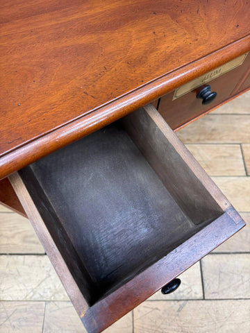 Antique mahogany drawer with brass label and black knobs on vintage mahogany apothecary style console table