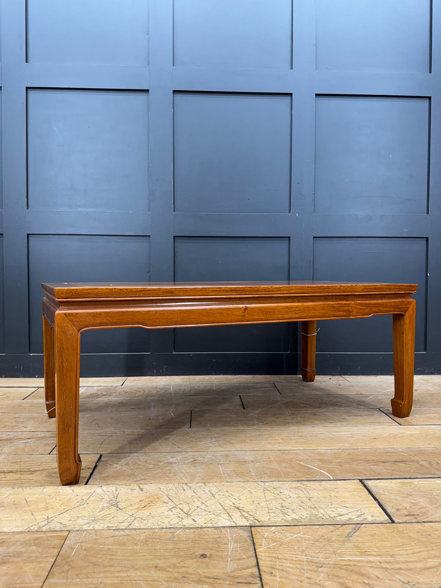 A polished medium-brown mahogany coffee table with a rectangular top and elegantly curved legs vintage mid century style