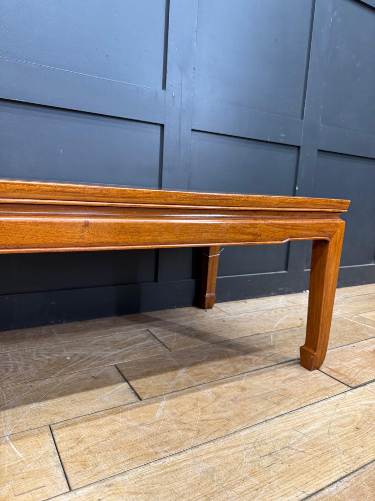A polished light brown vintage mahogany coffee table with a smooth finish and elegant tapered legs in mid century modern style