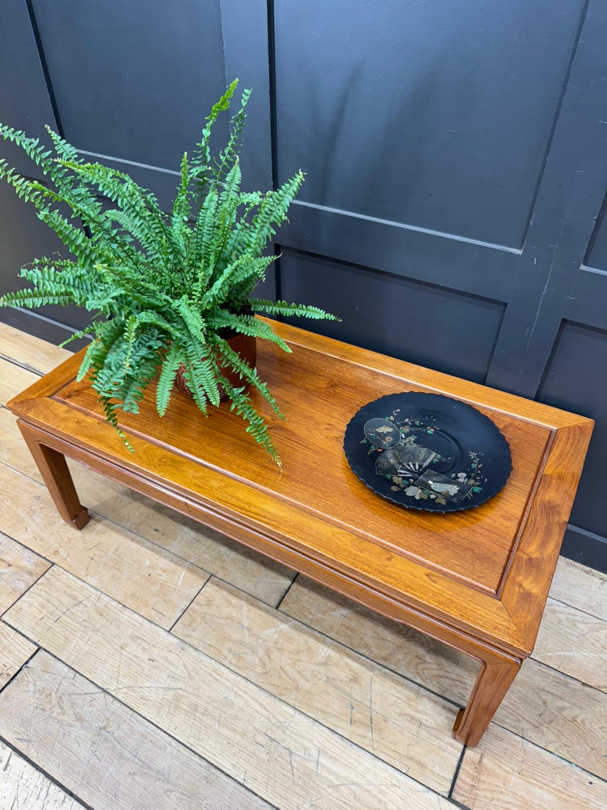 Vintage mahogany coffee table with warm amber finish raised edges green fern and black decorative plate on top