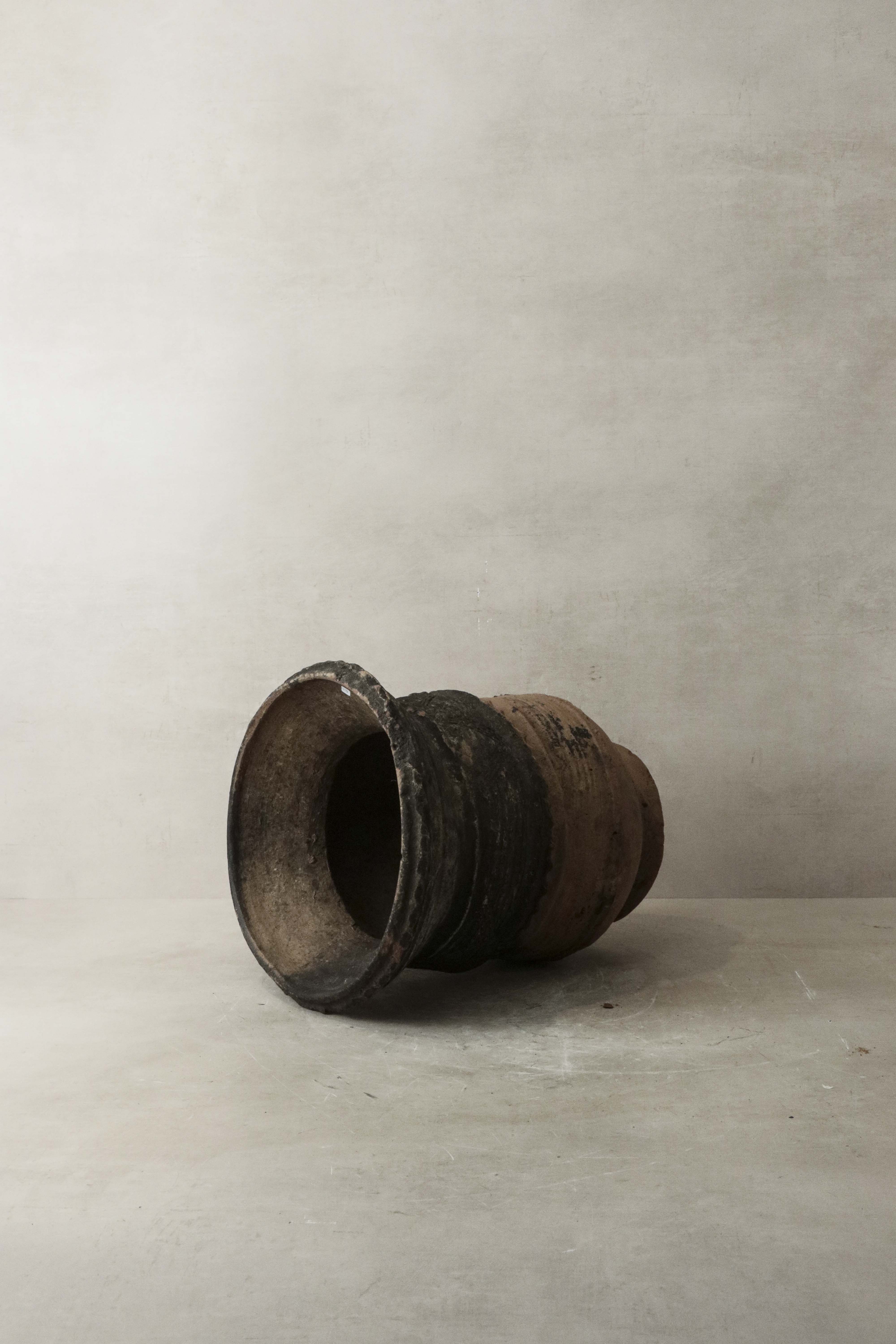 Vintage nupe pot stand featuring a weathered dark brown ceramic pot with a flared rim and visible wear