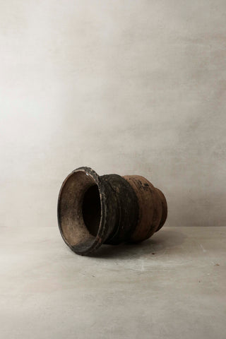 Vintage nupe pot stand featuring a weathered dark brown ceramic pot with a flared rim and visible wear
