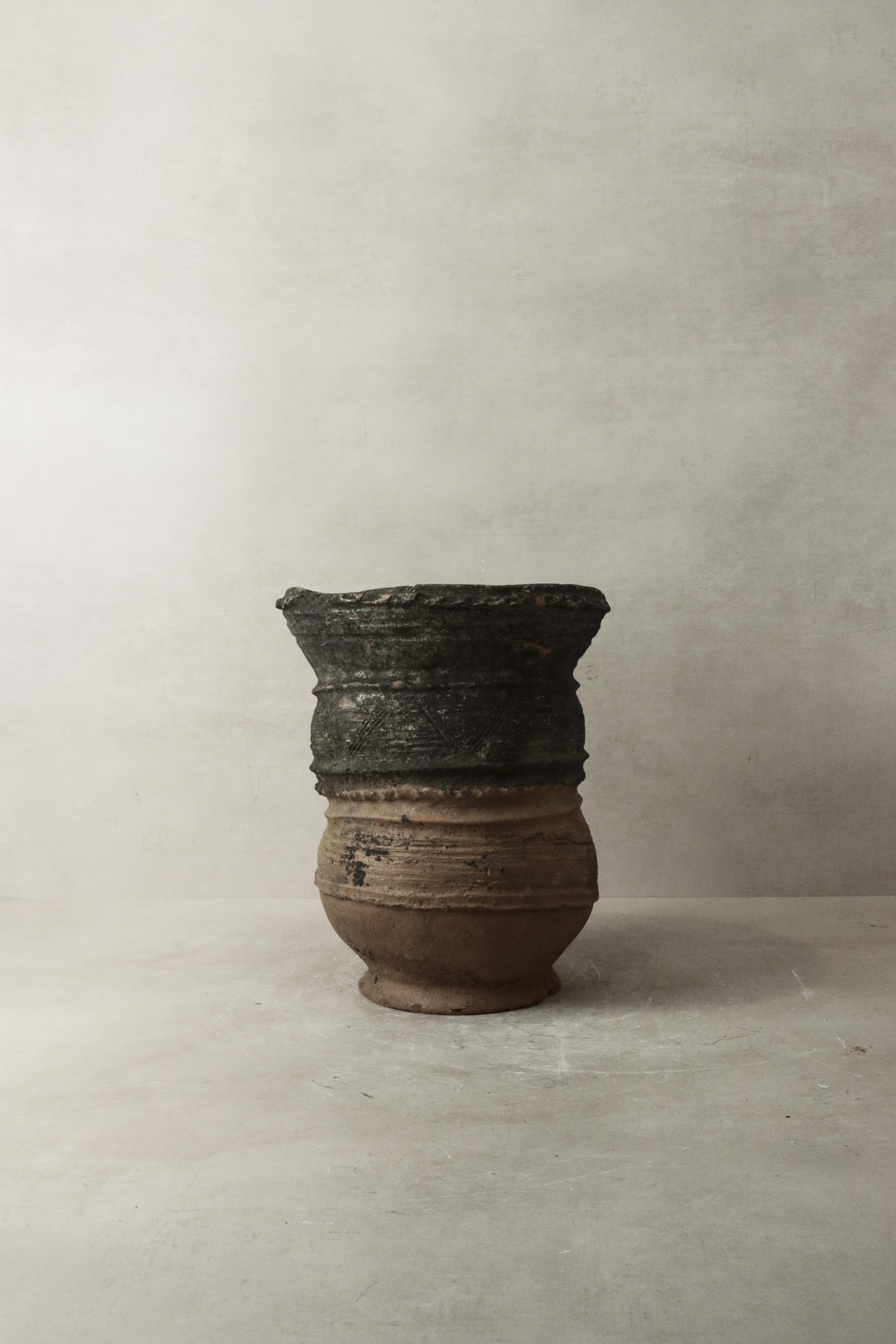 Vintage nupe pot stand 4.3 with a weathered two-toned ceramic pot featuring dark upper section and lighter brown base