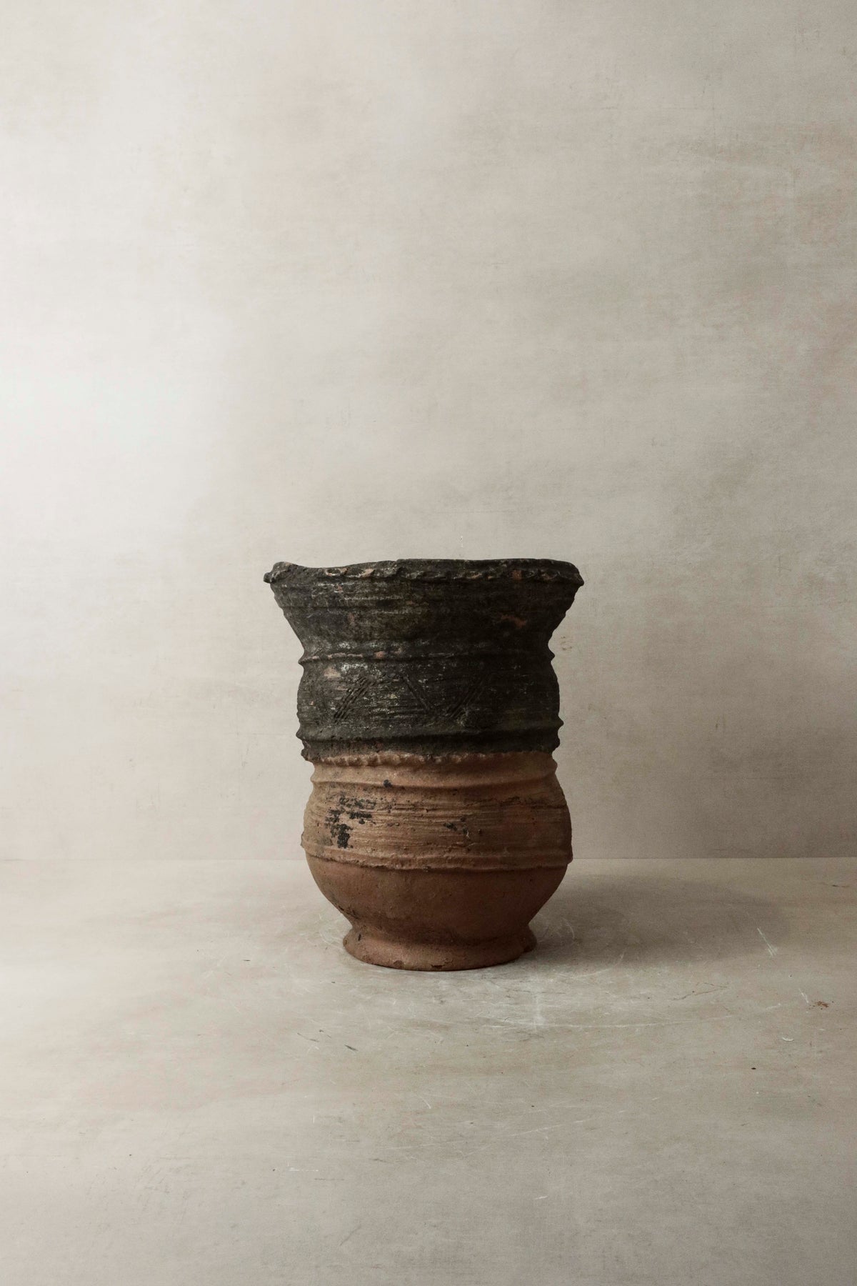 Vintage nupe pot stand 4.3 with a weathered two-toned ceramic pot featuring dark upper section and lighter brown base