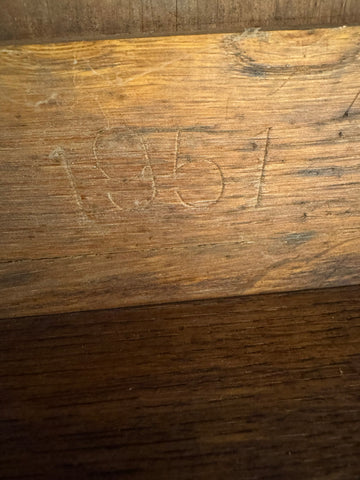 Vintage oak desk with hand carved 1957 engraving on rustic wooden plank showing warm amber tones and wood grain