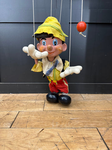 Vintage pelham puppets pinocchio marionette with yellow hat red trousers and painted face standing on wooden floor