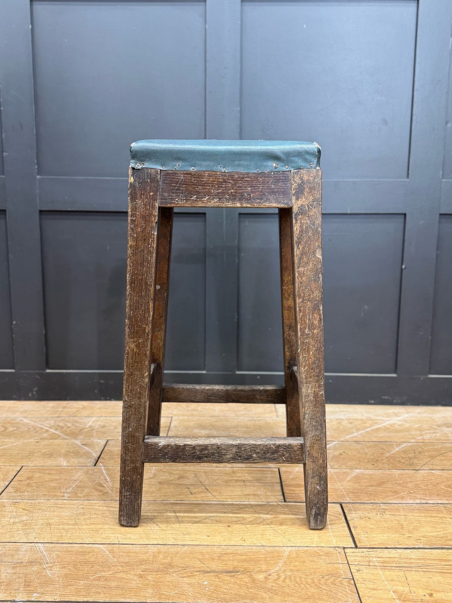 Vintage railway stool with dark brown weathered wood and teal green upholstered seat inspired by mid century train station seating