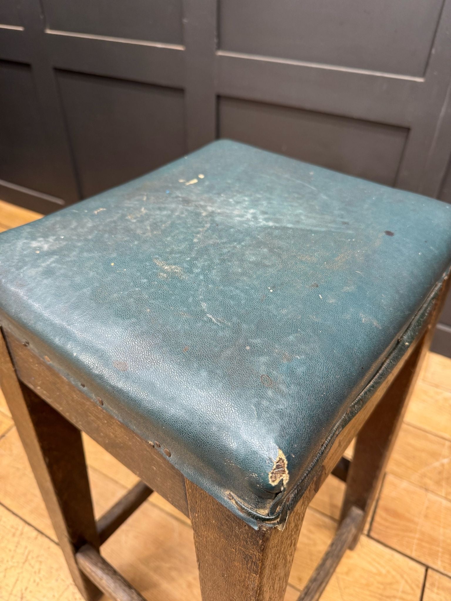 Worn teal leather seat of vintage mid century lner railway stool wooden bar stool seating