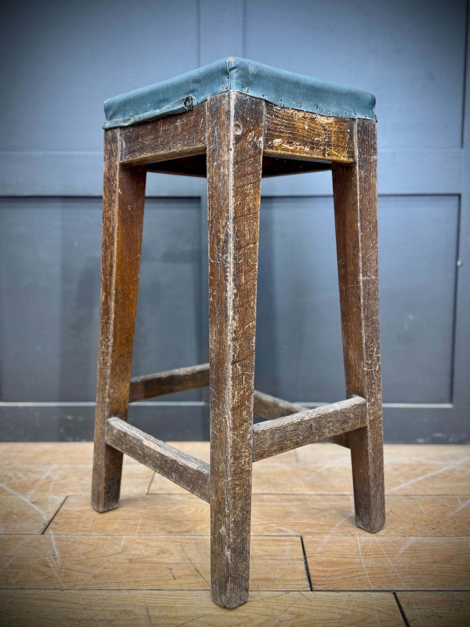 Rustic wooden railway stool with teal upholstered seat inspired by mid century LNER train station seating