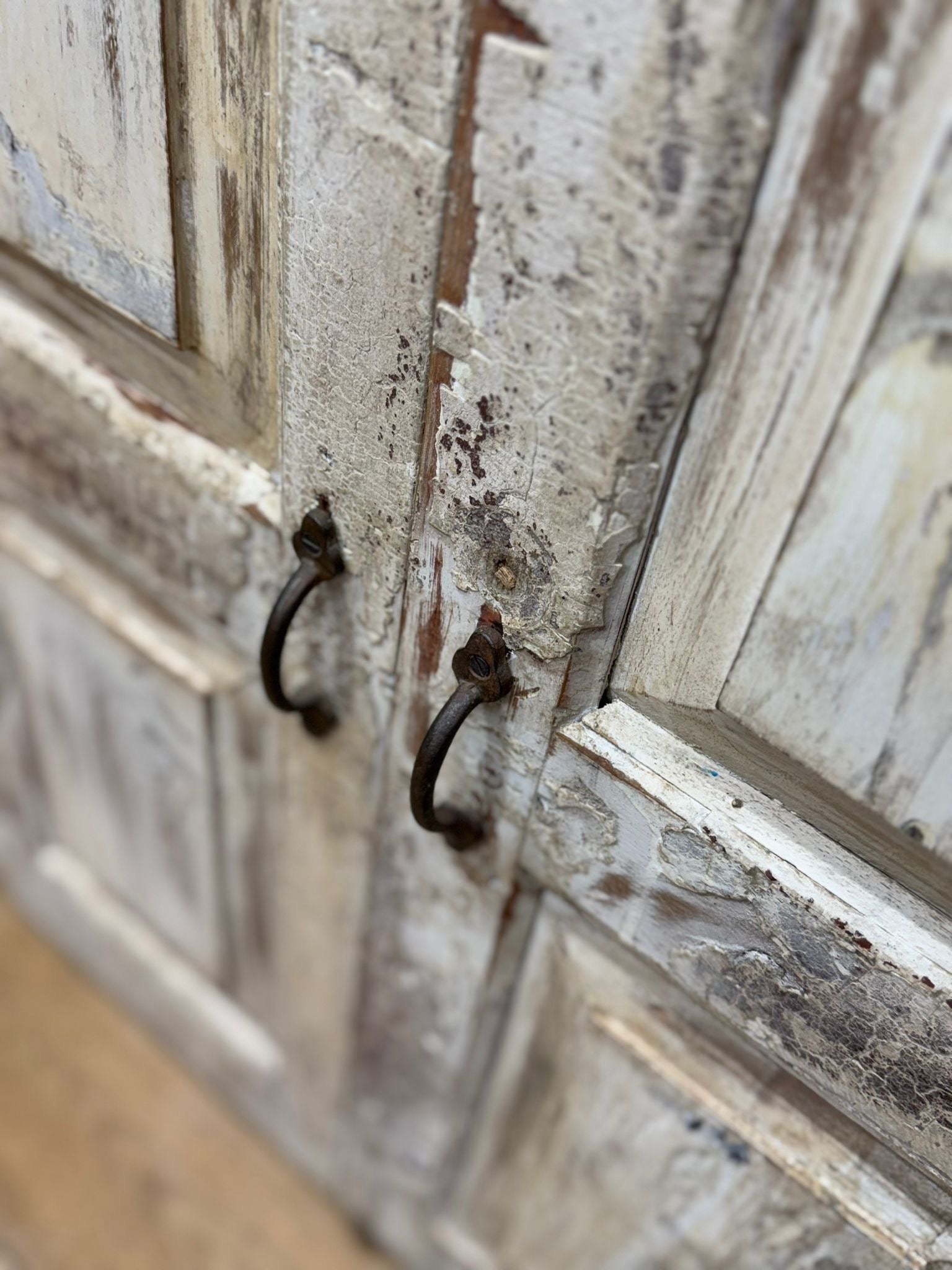 Vintage rustic cupboard with weathered white wooden door and dark rustic metal handles for bathroom or kitchen use