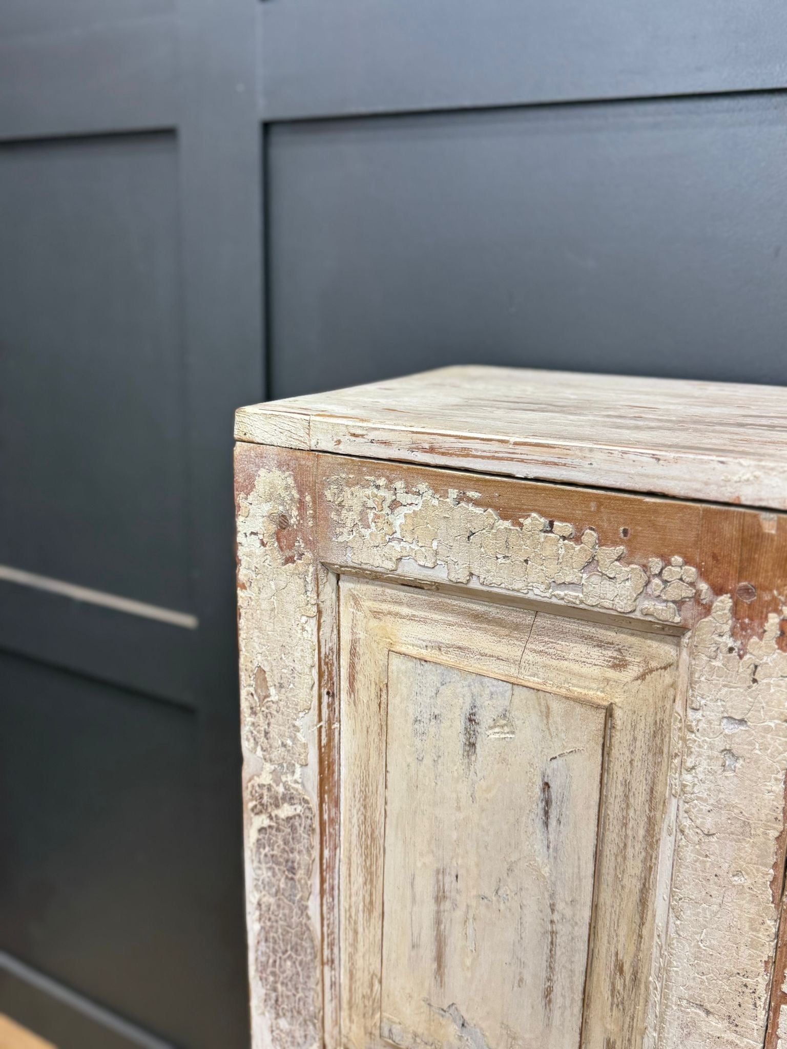 Vintage rustic cupboard with distressed white and brown paint finish showing wood grain and chipped surfaces