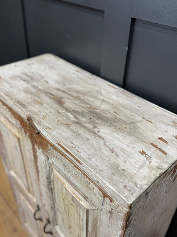 Vintage rustic cupboard with weathered white paint and distressed wood grain perfect for bathroom or kitchen use