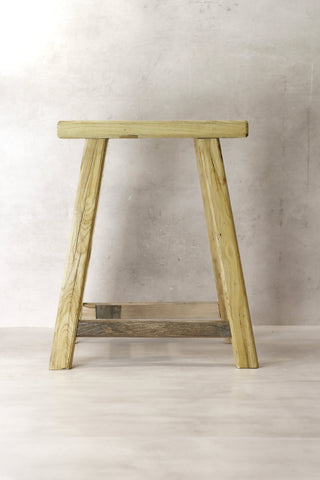 A vintage rustic elm wood stool in light green with a simple a-frame design and visible wood grain
