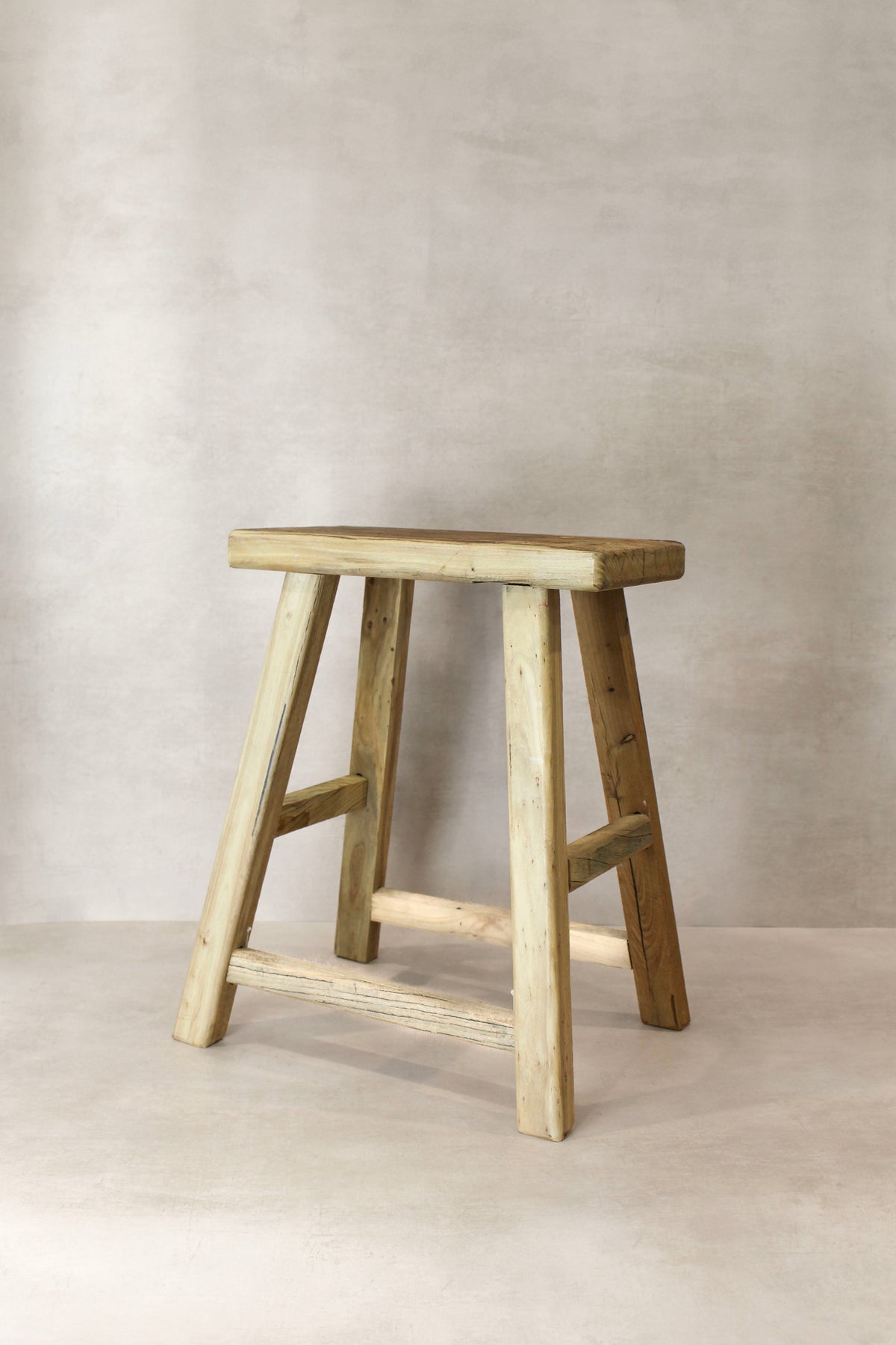 A vintage rustic elm wood stool with a weathered light beige finish and sturdy a-frame legs medium size