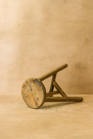 Vintage rustic elm wood stool with a round weathered seat and three angled legs wood stool perfect for cozy spaces
