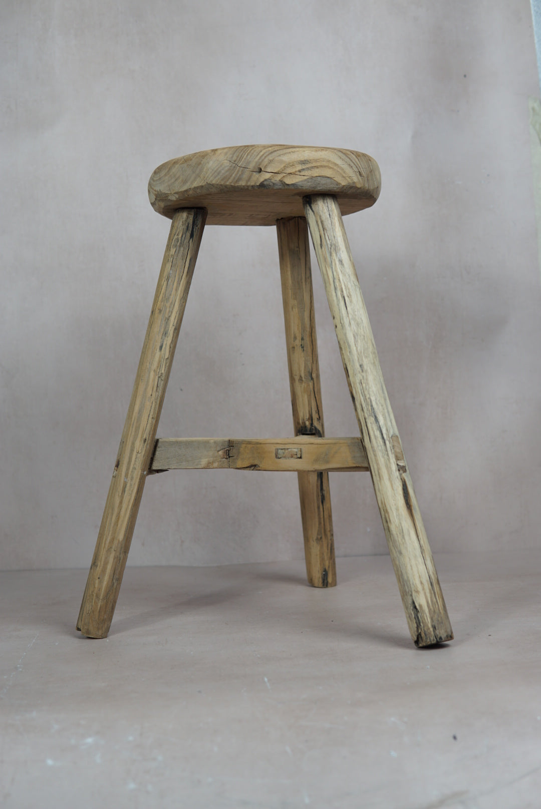 Vintage rustic elm wood stool with a round weathered seat and four sturdy legs perfect for cozy seating