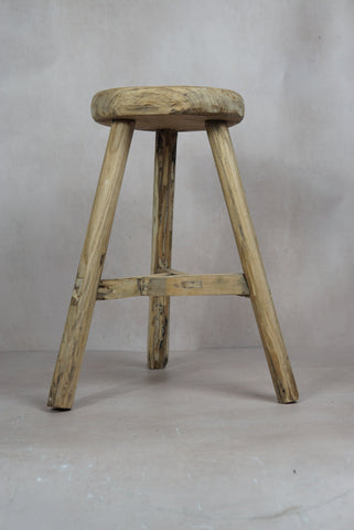 Vintage rustic elm wood stool with a round weathered seat and three sturdy legs connected by a support beam