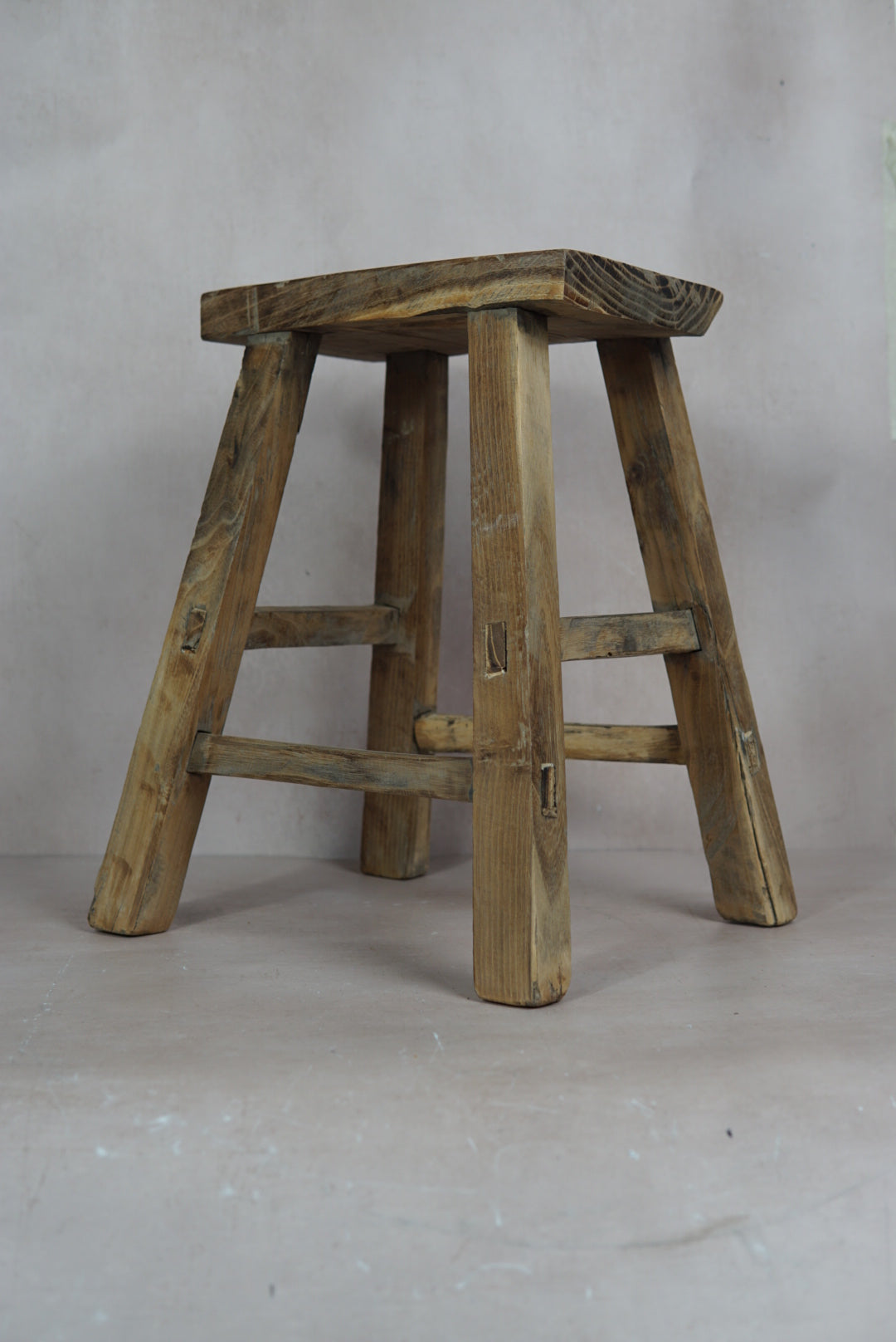 Vintage rustic elm wood stool with weathered natural finish and sturdy angled legs for timeless charm