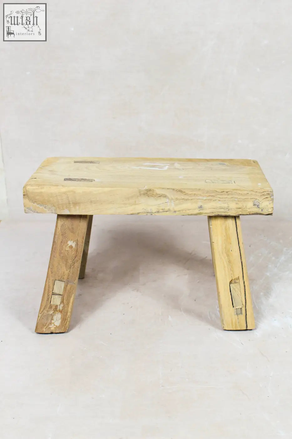 A vintage rustic elm wood stool with a light wooden rectangular seat and angled legs perfect for small spaces