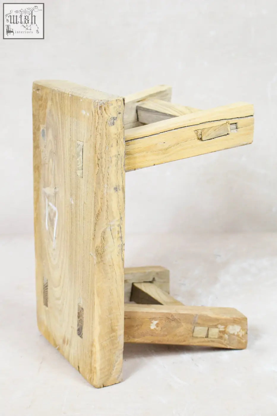 A vintage rustic elm wood stool in light color with visible grain and weathered edges perfect for small spaces