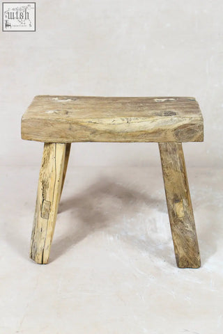 Vintage rustic stool made of elm wood with a weathered light brown finish and sturdy legs for small spaces