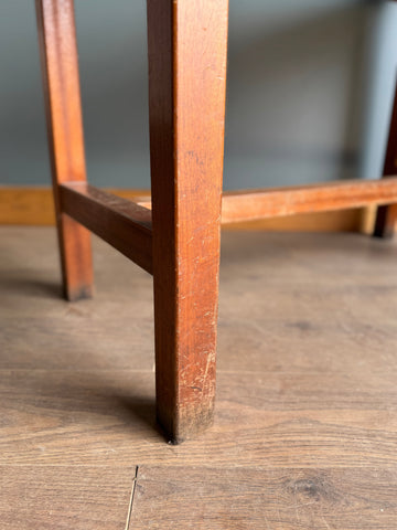 Worn medium brown wooden stool leg with scratches on vintage school science lab beech frame kitchen island table