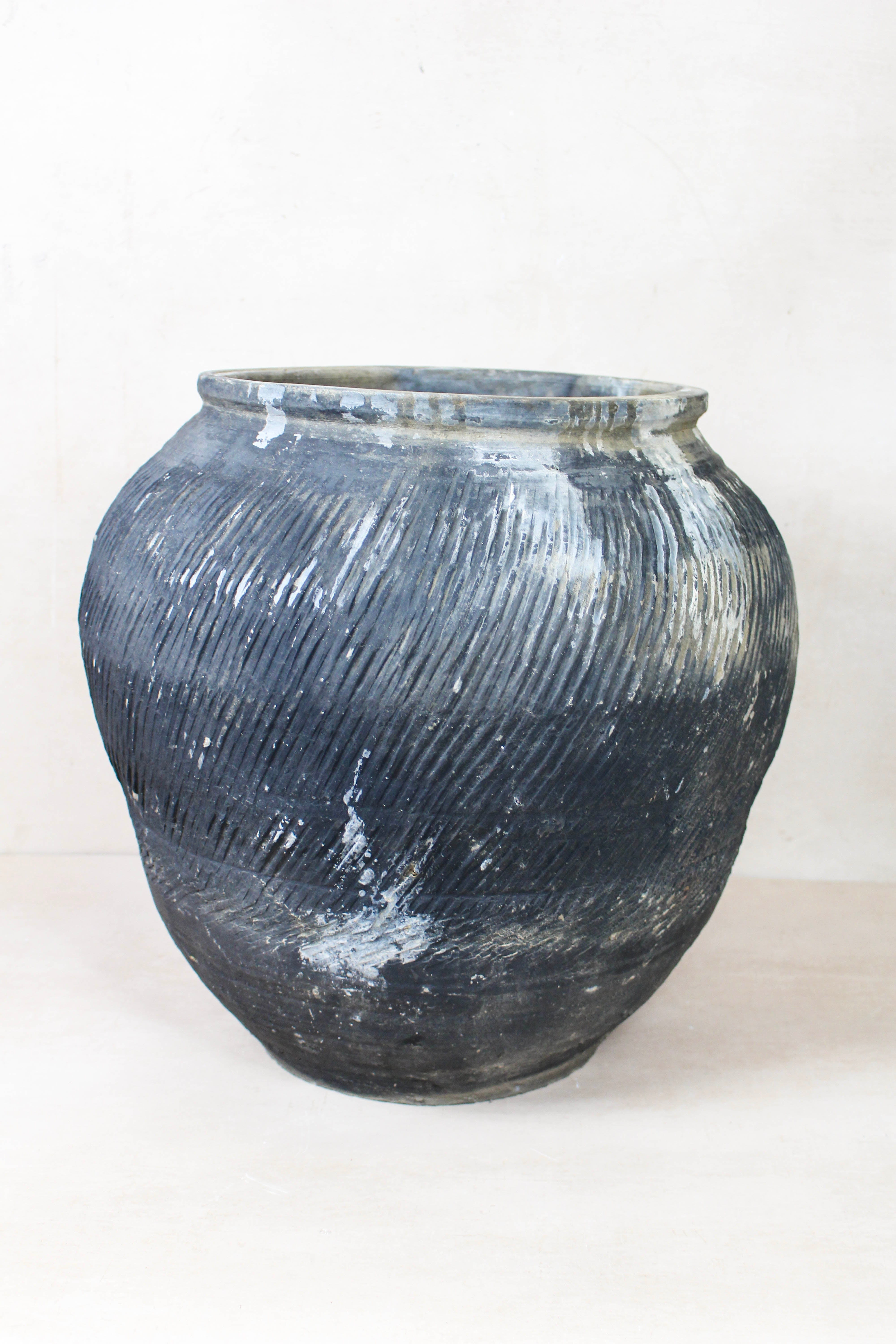 A vintage textured grey ceramic jar with diagonal ridges and subtle white patches perfect for rustic decor