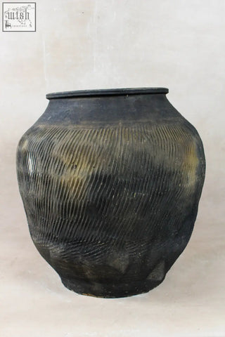 A vintage textured grey ceramic jar with ribbed pattern and golden brown streaks perfect for decor