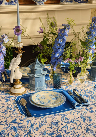A delicate blue and white porcelain dessert plate with floral pattern resting on a matching napkin set of 4