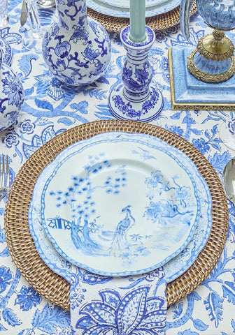 Blue and white porcelain dessert plate with delicate peacock design on woven wicker placemat set of 4
