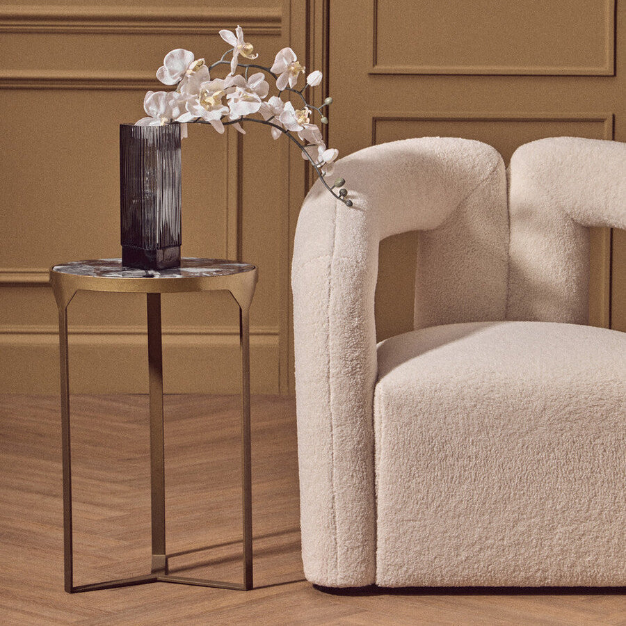 Cream-colored plush sheepskin armchair with rounded contours pairs perfectly with vizzini round agate side table