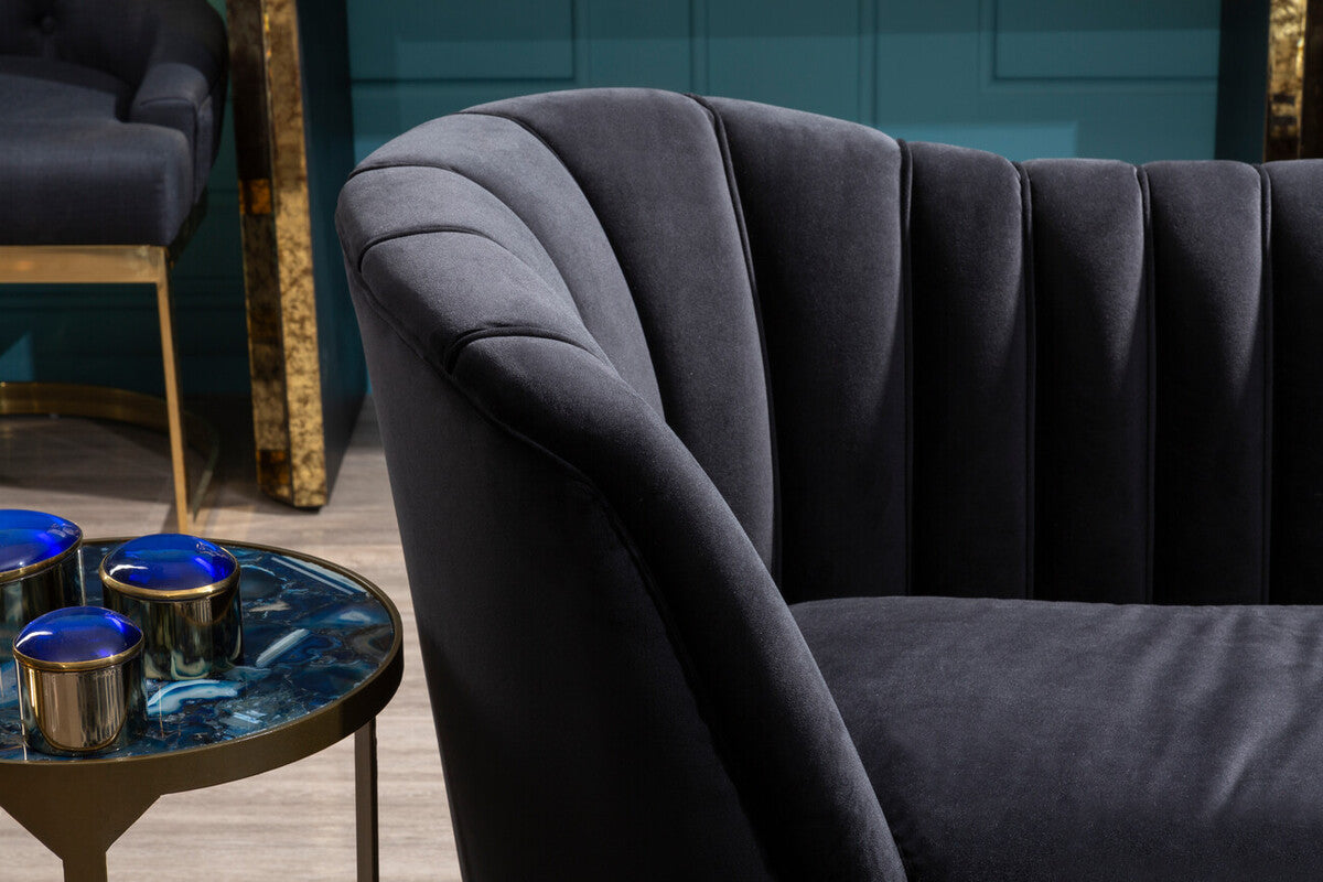 Dark gray velvet sofa with curved tufted backrest and plush seating next to vizzini round agate side table with antique brass