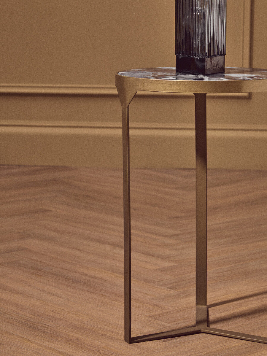 Gold-toned antique brass vizzini round agate side table with round marble top and vertical ridged glass vase on it