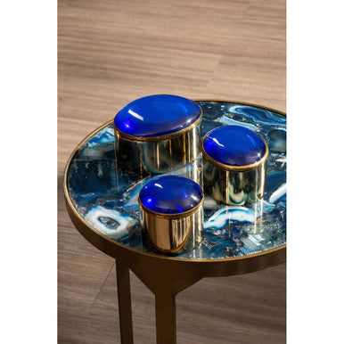 Three antique brass containers with blue lids on a vizzini round agate side table with swirling round agate top