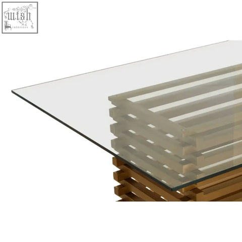 Modern matte gold dining table with glass top and wooden base featuring horizontal slats for stylish dining