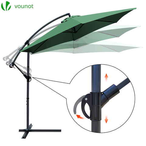 Green fabric canopy on a black metal cantilever garden parasol with crank handle for outdoor sun shade