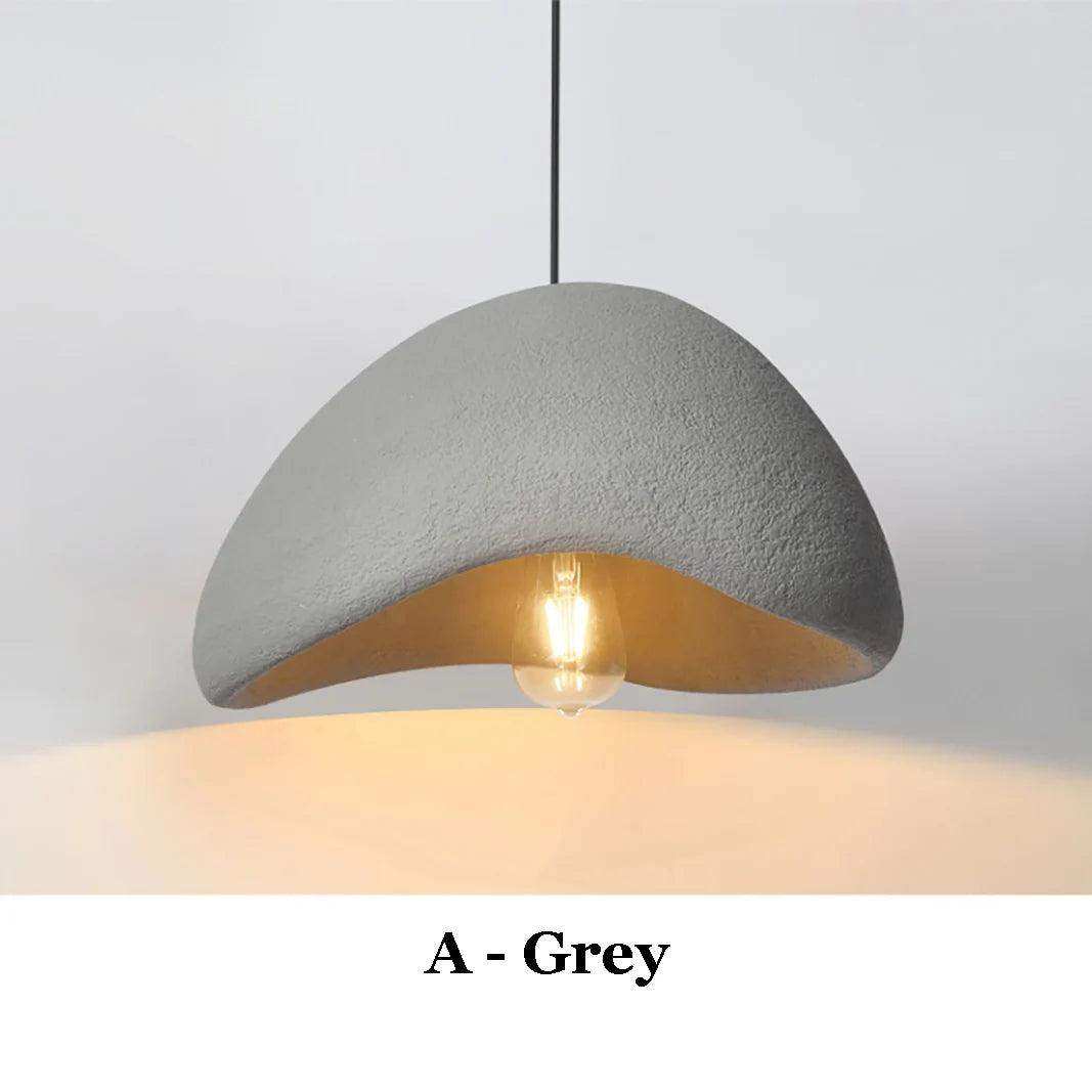 A modern grey concrete wabi sabi pendant light with a warm golden interior and exposed bulb