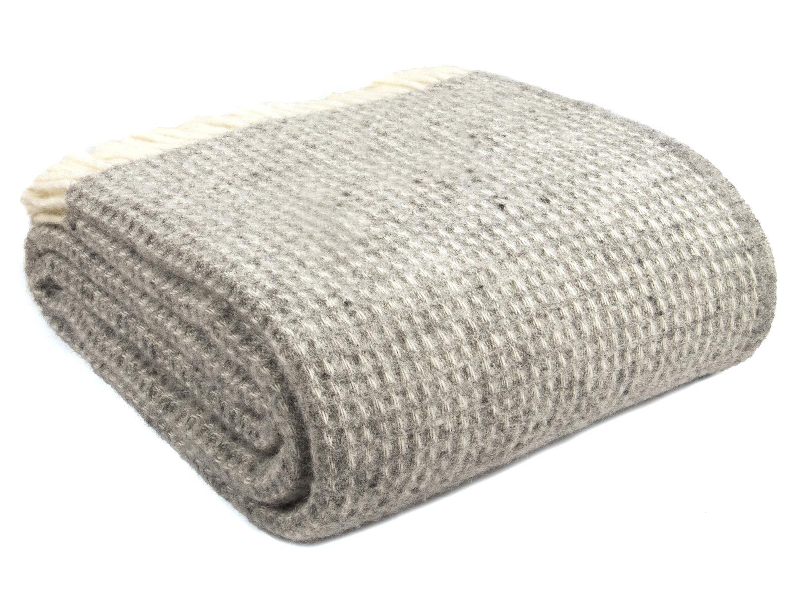 A neatly folded silver grey waffle xl pure new wool throw with a textured herringbone pattern and blanket size guide