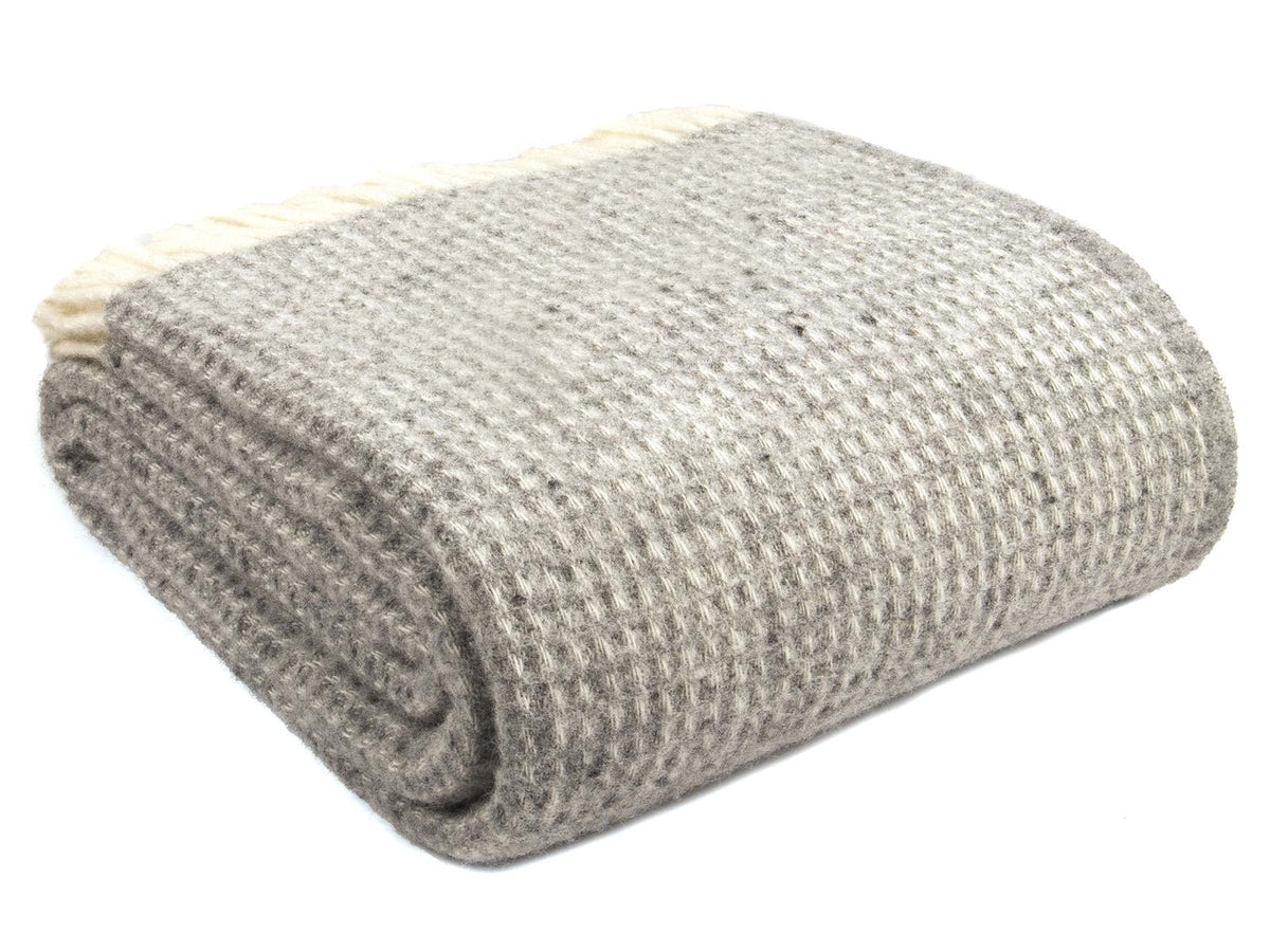 A neatly folded silver grey waffle xl pure new wool throw with a textured herringbone pattern and blanket size guide