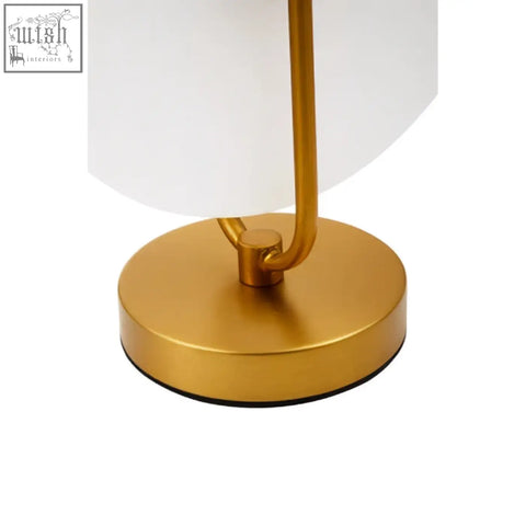 Gold finish table lamp with sleek curved stem and round base on a white marble table lamp base