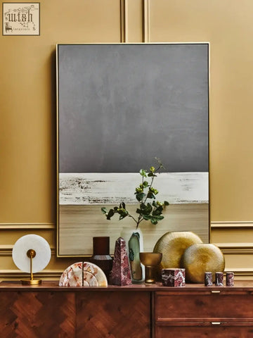 A minimalist abstract painting with gray and textured white bands featured with a marble table lamp