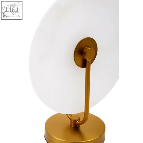 Gold-toned vanity mirror with a sleek white glass surface and minimalist frame paired with a marble table lamp